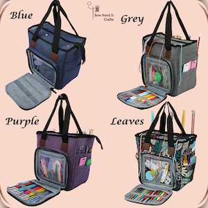 May include: Four different colored yarn totes with the words "Sew Need It Crafts" in the center of the image. The totes are open and show the inside compartments and pockets. The totes are labeled "Blue", "Grey", "Purple", and "Leaves".