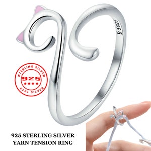 Op de afbeelding: Een zilveren ring in de vorm van een kat met roze oren. De ring is een spanningsring, wat betekent dat hij open en verstelbaar is. De ring is gemarkeerd met "925 Sterling Silver".