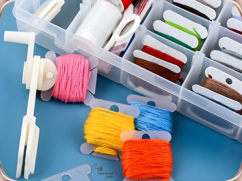 May include: A clear plastic craft organiser filled with spools of colourful embroidery floss in shades of pink, yellow, blue, and orange. A white thread winder and scissors are also visible.