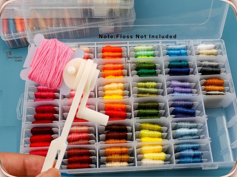 May include: A clear plastic storage box containing a selection of colourful embroidery threads. The threads are arranged in a variety of shades, including pink, red, orange, yellow, green, blue, and purple. A white thread winder is in the foreground. Text in the image reads "Note: Floss Not Included".