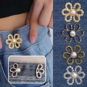 May include: Flower-shaped jean buttons in gold, silver, and bronze, each with a pearl centre. One button is attached to blue jeans. Additional buttons are displayed on a denim background.
