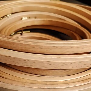May include: A stack of wooden embroidery hoops in various sizes. The hoops are made of light-colored wood and have a smooth, curved design. The brass hardware is visible. These are ideal for embroidery and cross-stitch projects.