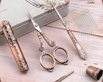 May include: A set of vintage-style sewing tools in a copper finish. The set includes a pair of scissors, a needle threader, a thimble, and a case for needles. The tools are arranged on a wooden surface. Sew Need It Crafts.
