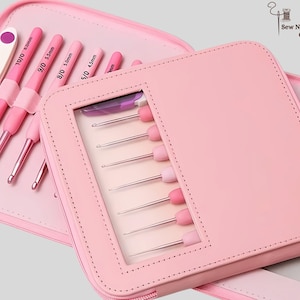 May include: A pink crochet hook set in a matching case. The case is open, revealing several crochet hooks with pink handles and silver hooks. The case has a clear window to display the hooks. The set includes a variety of hook sizes.