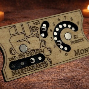 May include: Wooden game board with etched details, including a curved dial with numbers and a section labeled "Ki Points Monk." Features a map-like design and the words "Martial Arts." Two lit candles are in the background.