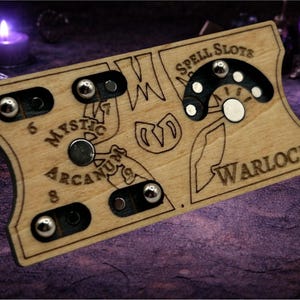 May include: A wooden game board with etched designs and the words "Spell Slots," "Mystic Arcanum," and "Warlock." It features magnetic markers and a circular dial. The board is light brown with dark etched details.