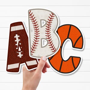 Könnte beinhalten: Drei dekorative Buchstaben A, B und C mit Sportmotiven. Der Buchstabe A ähnelt einem braunen Football mit weißen Schnürsenkeln, der Buchstabe B ist wie ein weißer Baseball mit roten Nähten und dem Buchstaben D geformt, und der Buchstabe C ist ein orangefarbener Basketball.