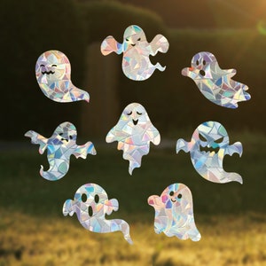 Op de afbeelding: Acht regenboogkleurige, holografische geesten-raamdecoraties. De geesten zijn in verschillende maten en vormen met een glinsterende afwerking.