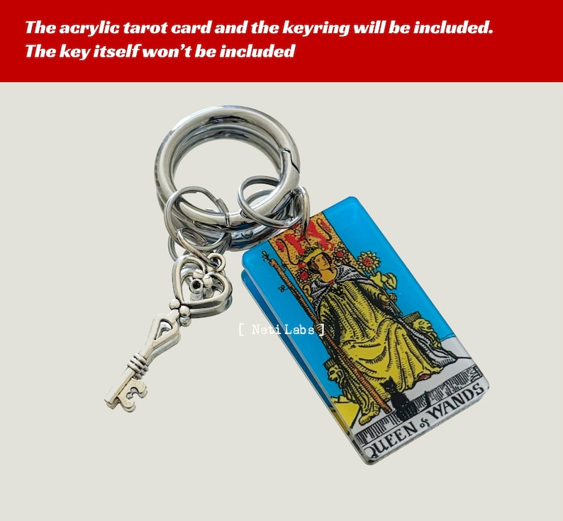 May include: A silver key charm attached to a silver keyring with a blue and white acrylic tarot card featuring the Queen of Wands. The card has a yellow and black illustration of a woman sitting on a throne with a staff and a black cat.