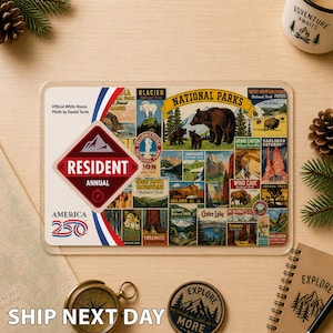 May include: A clear plastic Resident Annual America 250 National Parks pass with vintage-style illustrations of national parks. The pass features a red, white, and blue design and the text "Resident Annual".