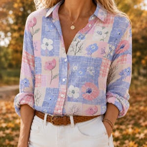 May include: A long-sleeved button-down shirt featuring a patchwork pattern of light blue, pink, and white squares with floral illustrations. The shirt is tucked into white pants and secured with a brown leather belt featuring a metal buckle.