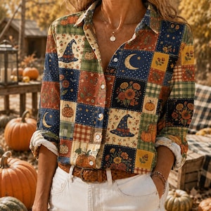 May include: A long-sleeve button-down shirt featuring a patchwork pattern of autumn-themed squares. The design includes illustrations of pumpkins, witch hats, crescent moons, and floral arrangements in shades of orange, blue, and green.