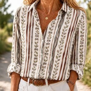 May include: A long-sleeved button-down shirt featuring a vertical pattern of brown leather-style belts interspersed with columns of green oak leaves and brown acorns on a white background, paired with a brown leather belt at the waist.