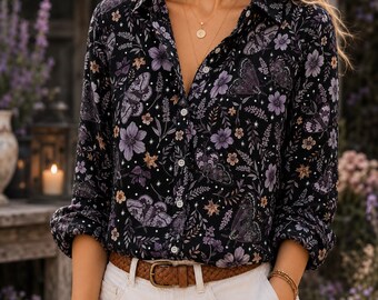 May include: A long-sleeved button-down shirt in black featuring a repeating pattern of purple flowers, moths, and small white stars. The shirt has a classic collar and is tucked into white trousers with a brown woven leather belt at the waist.