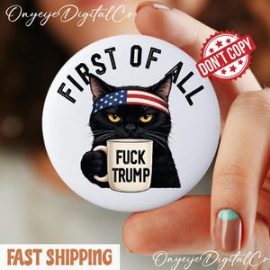 Op de afbeelding: Een witte button met een zwarte kat met een Amerikaanse vlag hoofdband, die een mok vasthoudt met de tekst "FUCK TRUMP". De button heeft ook de tekst "FIRST OF ALL" en een "DON'T COPY" stempel.