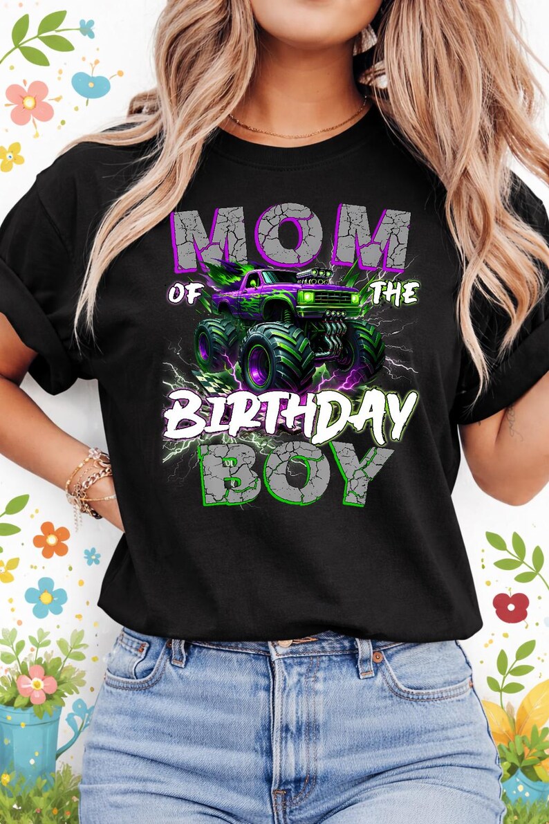 May include: Black t-shirt with a graphic featuring a purple and green monster truck. The text reads "MOM of the BIRTHDAY BOY" in a cracked, distressed font, with lightning bolt accents.