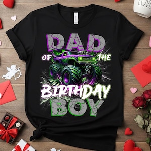 May include: Black t-shirt with a graphic of a monster truck in purple and green, with the text "DAD OF THE BIRTHDAY BOY" in a distressed font. The design includes lightning bolts and a checkered flag.