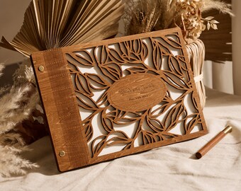 May include: A wooden guest book with a leafy design and the text "William & Sophia" and "Dec. 11th, 2022" engraved on the front.