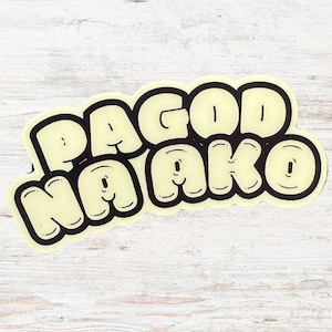 May include: A cream-coloured sticker featuring the words "PAGOD AKO" in a bold, rounded font with a black outline. The design has a playful, cartoonish aesthetic, suitable for customising belongings. The text is centrally positioned.