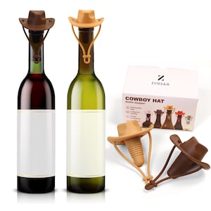 May include: Two wine bottles with blank labels are topped with brown and tan cowboy hat bottle stoppers. A box with the text "Cowboy Hat Bottle Stopper" and two additional stoppers are also visible.
