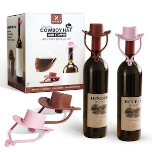 May include: A set of silicone cowboy hat wine stoppers in brown and pink. The packaging box displays the product and text: "Silicone Cowboy Hat Wine Stopper". The wine bottles have labels. The stoppers are airtight, reusable, and food-grade.