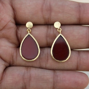 May include: A pair of gold teardrop earrings with red gemstone accents.