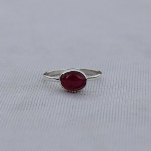 May include: A silver ring with a round, red gemstone.