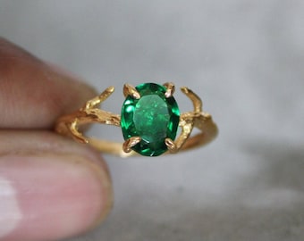 May include: Gold ring with a green oval gemstone set in a branch-like design.