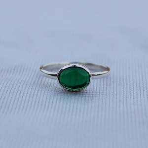 May include: A silver ring with a green oval gemstone.