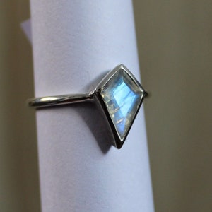 May include: A silver ring with a light blue moonstone set in a diamond shape.