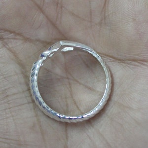 May include: A silver ring with a twisted band and a textured finish.