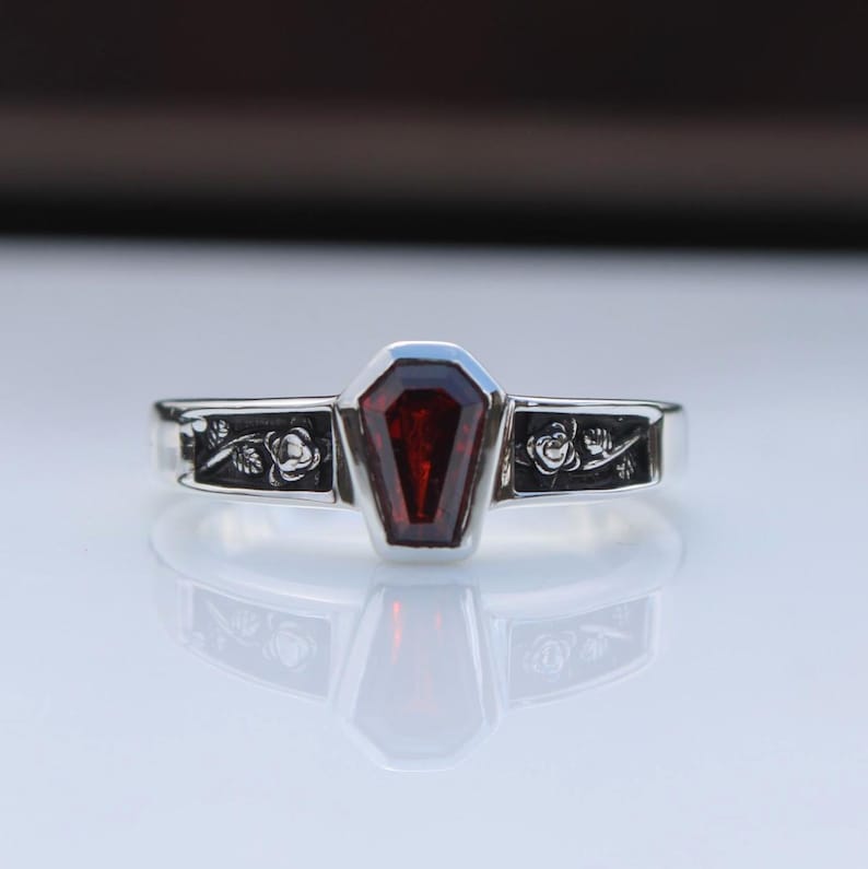 K&ouml;nnte beinhalten: Silberring mit einem Sarg-f&ouml;rmigen, tiefroten Edelstein. Das Band ist mit floralen und Blattmustern verziert. Der Ring hat ein gotisches und einzigartiges Design.