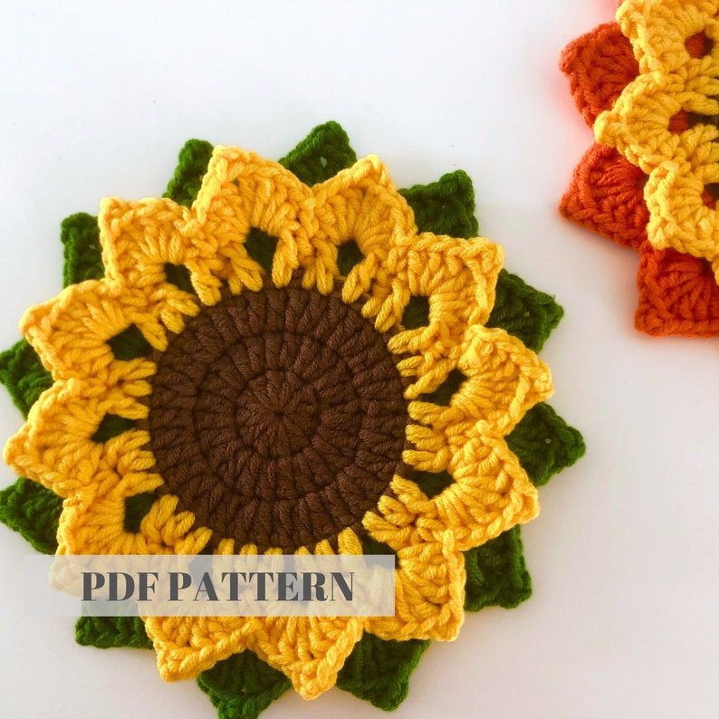 May include: Crochet pattern for a sunflower coaster. The coaster is made with yellow, brown, and green yarn. The pattern is available as a PDF download.