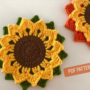 May include: Two crocheted sunflower coasters, one yellow and green, the other orange and brown. The coasters are made with a detailed crochet pattern and have a round center. The image includes the text "PDF PATTERN".