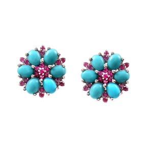 May include: A pair of flower-shaped stud earrings. Each earring features six oval turquoise stones surrounding a cluster of small, round, pink gemstones. The earrings are set in a silver metal.