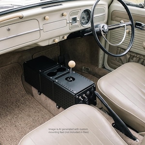 May include: A black metal center console with a perforated design, two circular cup holders, and a gear shift lever with a round wooden knob, installed between the beige front seats of a vintage vehicle with a matching beige dashboard and steering wheel.