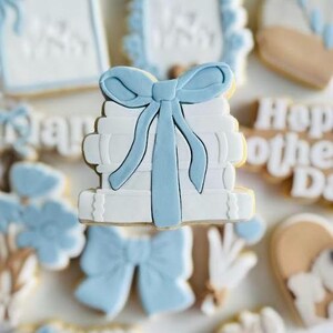 May include: A stack of white books tied with a light blue bow. The books are decorated with a white background and a light blue bow.