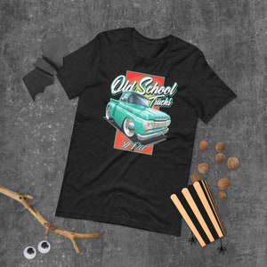 May include: Dark grey t-shirt with a teal vintage truck graphic, the text "Old School Trucks" and "'59 F100". The graphic is set against a red and yellow background. The shirt is made of a soft material.
