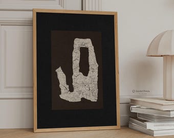 May include: A framed wall art print featuring a light beige, textured, abstract organic shape centered on a dark brown background. The artwork is enclosed in a thin, light-toned wooden frame with a wide black matting border surrounding the central image.