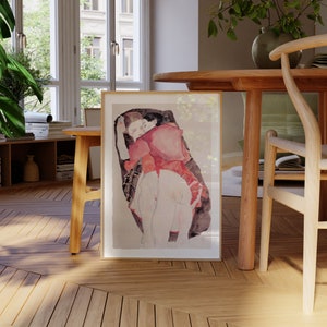 Puede incluir: Una l&aacute;mina art&iacute;stica enmarcada que presenta una ilustraci&oacute;n en acuarela de dos figuras abrazadas. Las figuras est&aacute;n representadas en tonos rojos, bronceados y marr&oacute;n oscuro sobre un fondo neutro. La obra est&aacute; en un marco sencillo de color claro.