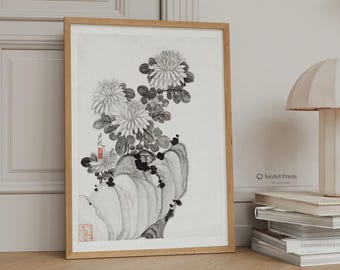 May include: A framed monochrome floral art print. The artwork depicts chrysanthemums and foliage in a detailed illustration. The print is in a wooden frame and rests on a light-coloured surface. The style is reminiscent of traditional Asian art.