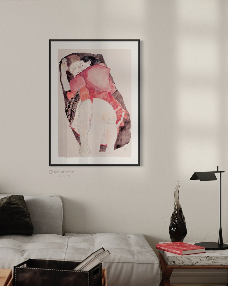 Puede incluir: Una l&aacute;mina art&iacute;stica enmarcada que muestra una ilustraci&oacute;n estilo acuarela de dos figuras abrazadas. Las figuras tienen tonos de piel p&aacute;lidos, una viste una prenda roja, sobre un fondo oscuro y abstracto dentro de un marco negro.