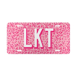 May include: Pink license plate with a leopard print background and white letters that spell "LKT"