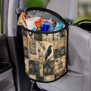 May include: Black and beige car trash bag with a raven and cage design. The bag is hanging from a car seat headrest and is filled with snacks and drinks. The bag has a zippered top and side pockets.