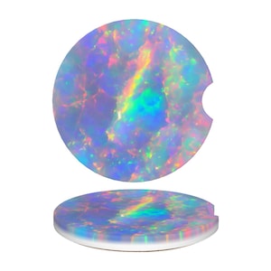 May include: Two car coasters with a vibrant, iridescent opal design. The coasters are round with a small notch on one side. The colors shift from blues and purples to greens and yellows, creating a shimmering effect. The coasters are set against a white background.