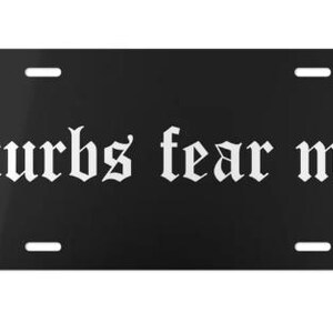 Puede incluir: Placa de matr&iacute;cula negra con la frase "curbs fear me" en fuente g&oacute;tica blanca. La placa tiene cuatro orificios de montaje y un acabado brillante. Un accesorio llamativo.