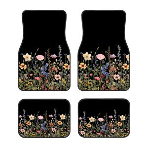 May include: Set of four black car floor mats with a floral design. The mats feature a border of colorful pressed flowers on a black background.