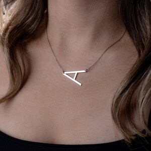 May include: A silver necklace with a large, open letter A pendant.