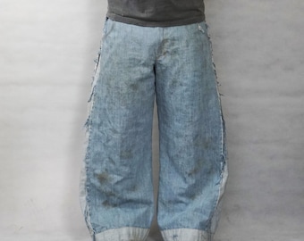 May include: Light blue denim jeans with an extremely wide-leg, baggy silhouette. The pants feature distressed, frayed side seams and a light wash finish with subtle darker patches. The hem is wide and straight, paired with dark sneakers.