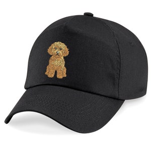 May include: Black baseball cap with an embroidered Cavapoo dog in shades of golden-brown. The cap has a curved peak and an adjustable strap. The dog is shown sitting, with detailed fur and facial features. A casual accessory for dog lovers.